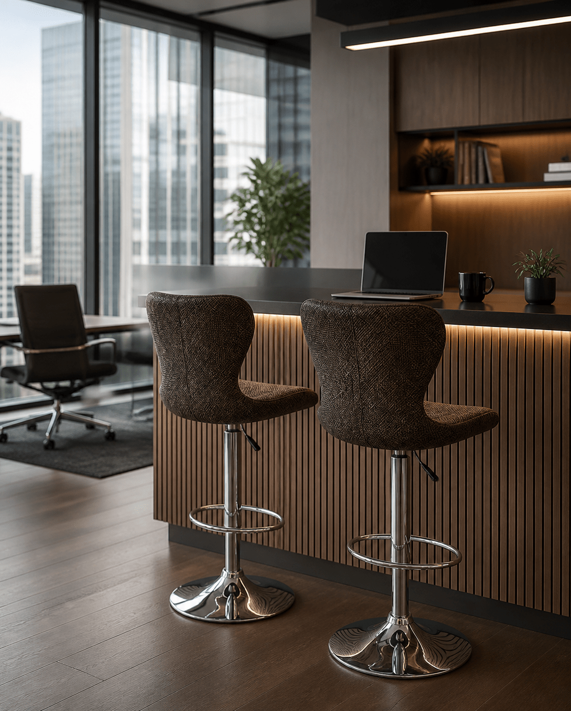 Two modern bar stools with textured brown fabric seats and chrome metal bases, positioned in front of a slatted wood counter in a contemporary office setting.