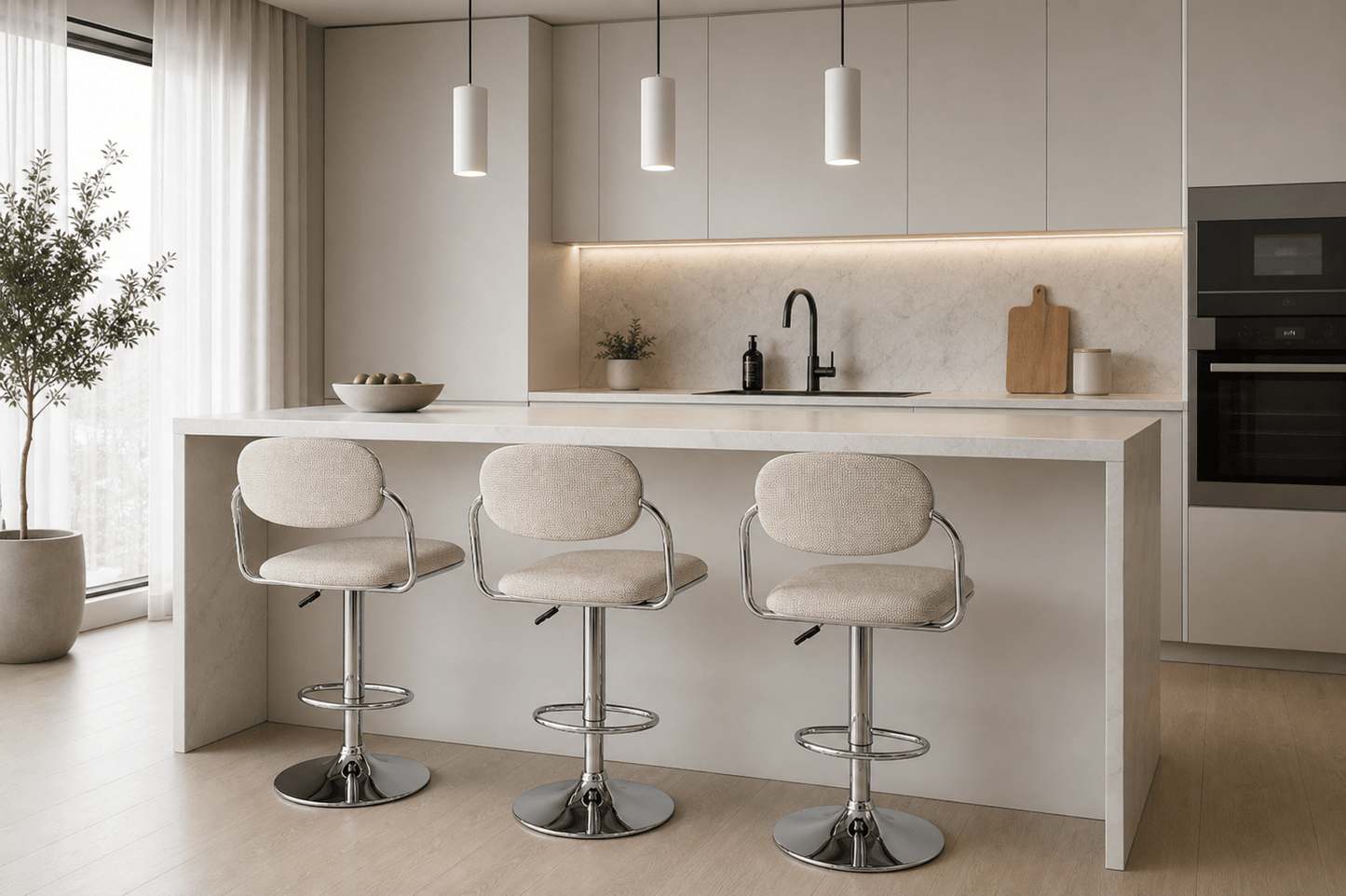 A modern kitchen island with a white countertop and three upholstered bar stools with chrome bases, set in a bright, minimalist kitchen with light wood floors and beige cabinetry.