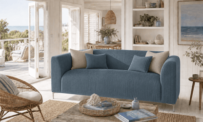Blue sofa in a bright living room with large windows and a view of the ocean. That Couch Place