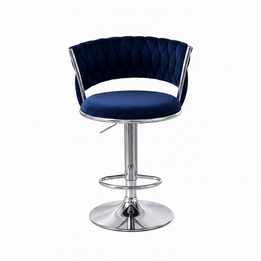 A old fashioned swivel bar stool with a deep navy blue velvet seat and tufted curved backrest, supported by a polished chrome metal pedestal base and footrest, set against a plain white background.