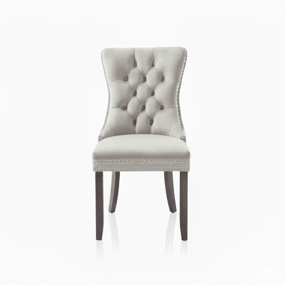 Cream upholstered chair with buttoned backrest and nailhead trim on a white background