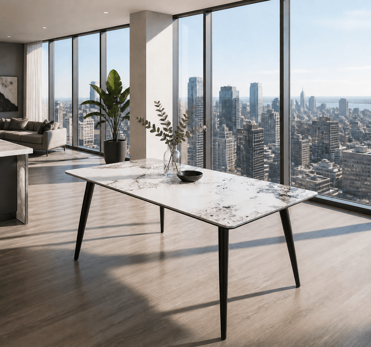 A modern rectangular dining table with a white marble-patterned top and black tapered legs, styled in a bright, contemporary loft apartment with large floor-to-ceiling windows overlooking a city skyline.
