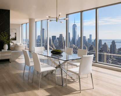 Modern dining room with a glass-top rectangular table and six white upholstered chairs, set in a high-rise apartment with large floor-to-ceiling windows overlooking a city skyline.