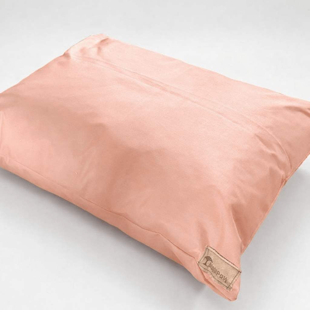 Pink dog pillow with a brand label on a light gray background