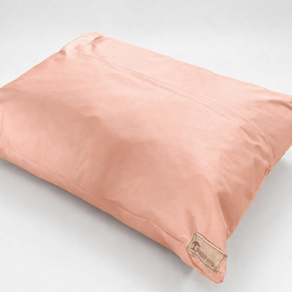Pink dog pillow with a brand label on a light gray background