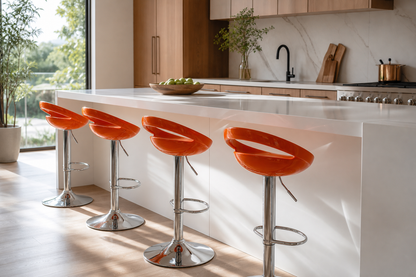 Four modern bar stools with bright orange curved seats and chrome pedestal bases arranged around a white kitchen island in a sunlit contemporary kitchen.