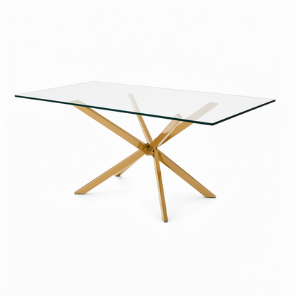 A modern 6 seater gold rectangular dining table with a clear glass top and a polished gold-tone metal X-shaped base, shown on a solid white background.