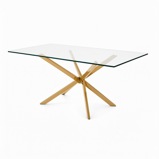 A modern 6 seater gold rectangular dining table with a clear glass top and a polished gold-tone metal X-shaped base, shown on a solid white background.