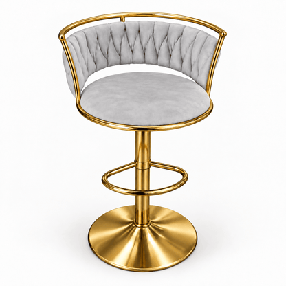 A modern swivel bar stool with a light gray tufted velvet seat and backrest, supported by a polished gold-finished metal frame and circular pedestal base.