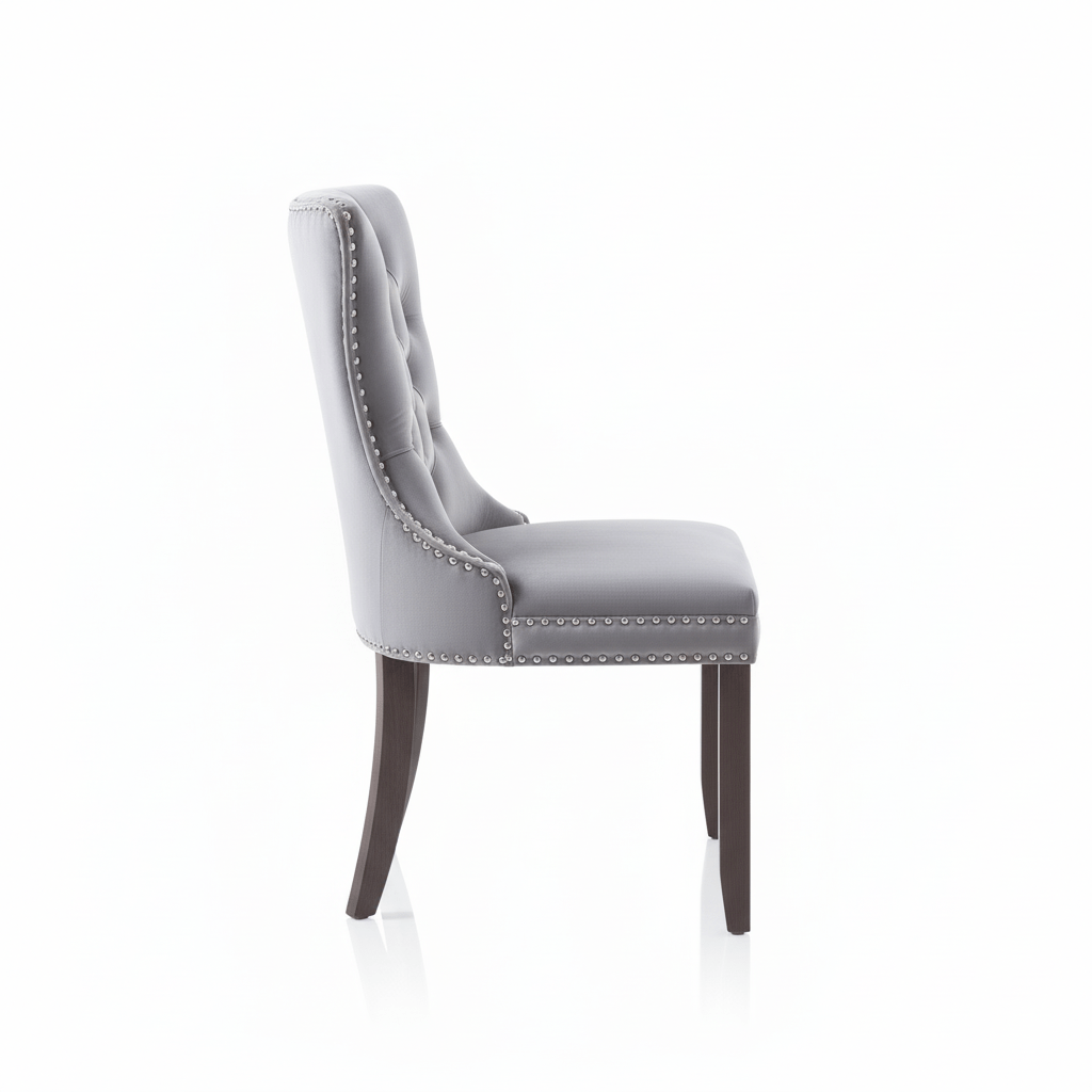 Side view of a grey upholstered dining chair with stud trim on a white background That Couch Place