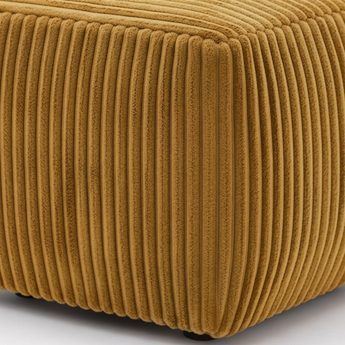 A close-up of a mustard yellow corduroy ottoman or stool, showing the ribbed fabric texture and corner seam.