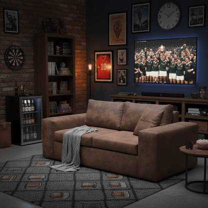 Living room with brown 2 seat sofa, sports-themed decor, and television showing a sports team. The Couch Place