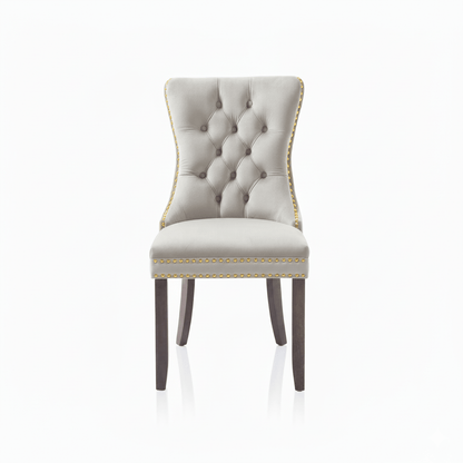 Cream Velvet upholstered chair with tufted backrest, gold studs and wooden legs on a white background 
