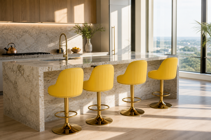 Four modern bar stools with bright yellow upholstered seats and brushed gold bases arranged around a marble kitchen island in a sunlit contemporary kitchen.