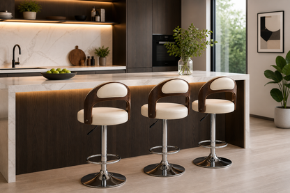 Three modern bar stools with cream leather seats and dark wood backs are arranged along a white marble kitchen island in a contemporary kitchen setting.