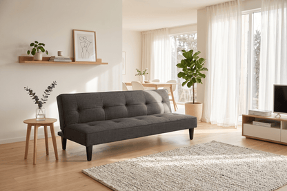 Gray sofa bed in a modern living room with wooden floor and large windows.