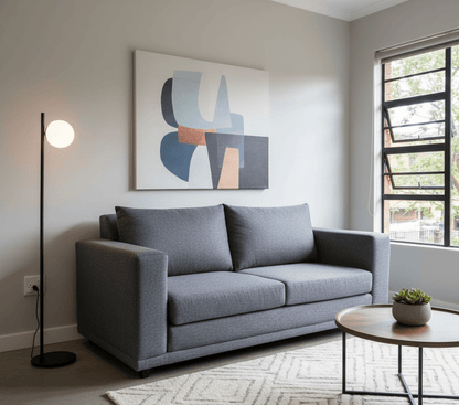 Modern living room with a Gray fold open full foam sleeper couch, round coffee table, and abstract art on the wall. That Couch Place